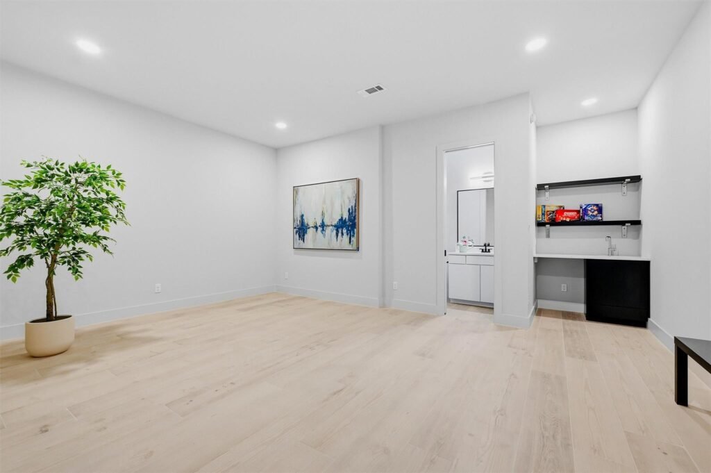 Minimalist living space with a tall potted plant and abstract wall art in the center-left of the room.