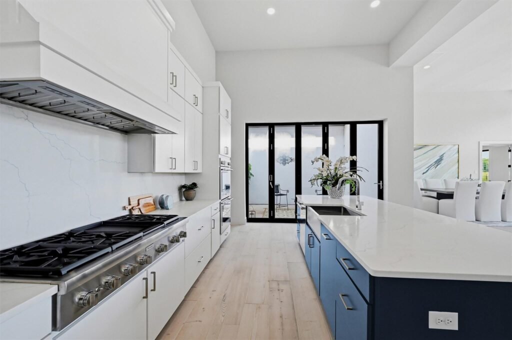 Bright, modern kitchen with white cabinets, stainless steel range, and a blue island centerpiece.